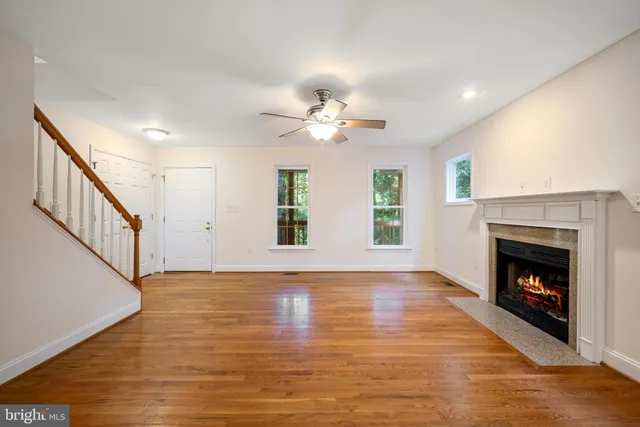 a view of an empty room with wooden floor fireplace and a window
