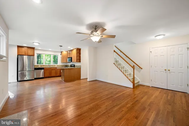 a view of an empty room with wooden floor a ceiling fan