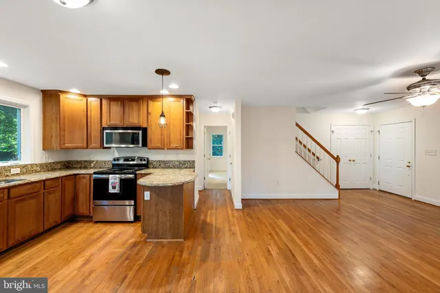 a kitchen with stainless steel appliances granite countertop wooden floors and white cabinets
