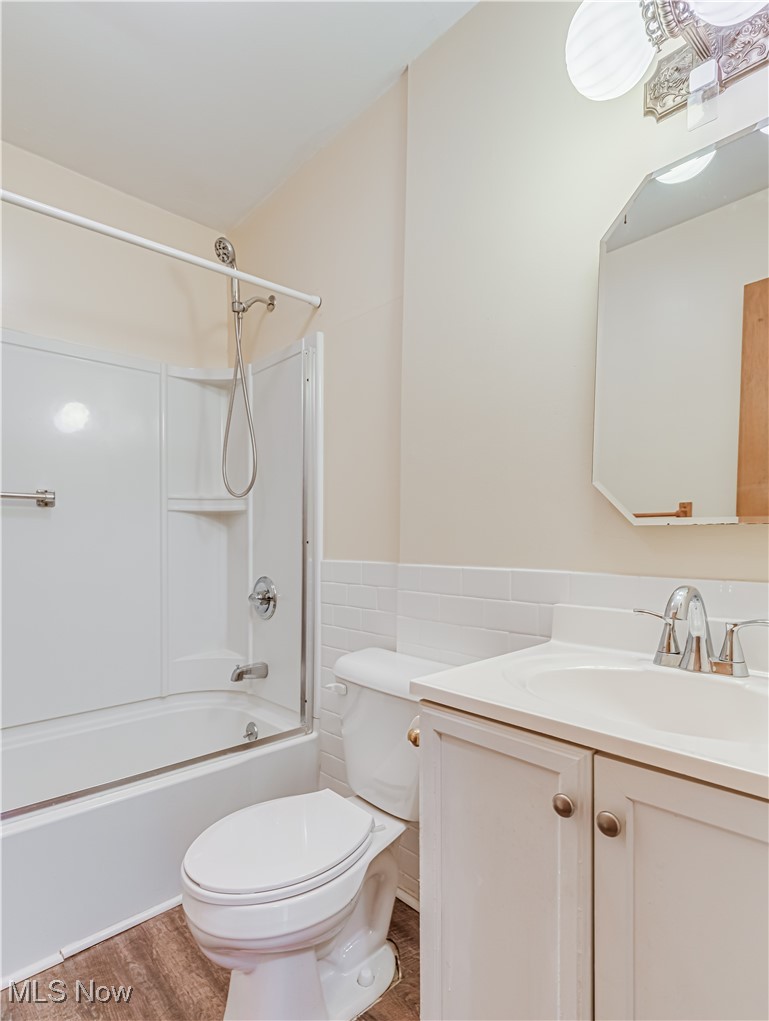 1014 Lilly Road Alliance, OH 44601 - Photo 16 of 19 Full bathroom featuring vanity, tile walls, wood-type flooring, bathing tub / shower combination, and toilet