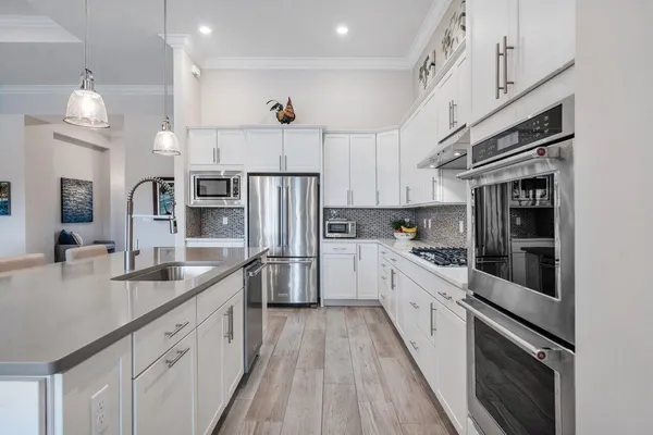 a living room with furniture kitchen view and a chandelier