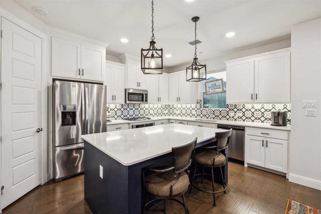 9408 Lamar Street, Unit D Rowlett, TX 75089 - Photo 1 of 1 a kitchen with kitchen island a stove a sink a refrigerator and chairs