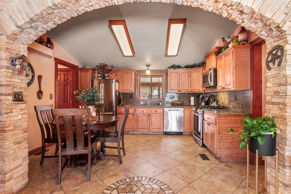 a kitchen with stainless steel appliances granite countertop a refrigerator a sink a stove and chairs