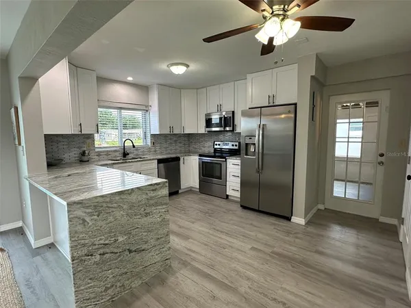 a kitchen with stainless steel appliances granite countertop a sink a stove a refrigerator cabinets and wooden floor