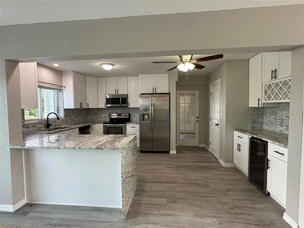 a kitchen with stainless steel appliances granite countertop a refrigerator a stove and a sink with wooden floor