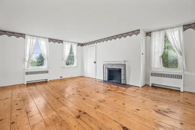 a view of empty room with wooden floor and fireplace