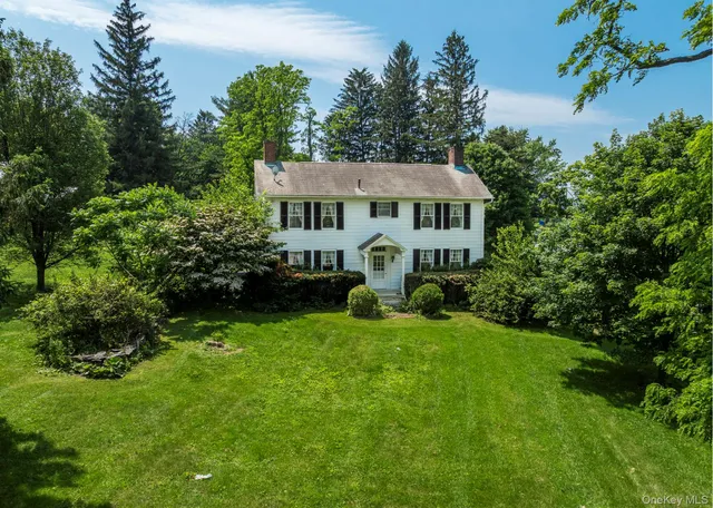 a view of a house with a big yard plants and large trees