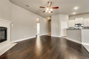 698 Harper Drive Fate, TX 75087 - Photo 2 of 18 an empty room with wooden floor fireplace and kitchen view