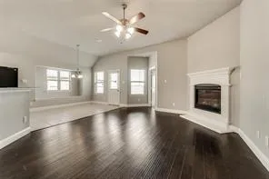 a view of an empty room with wooden floor and a fireplace