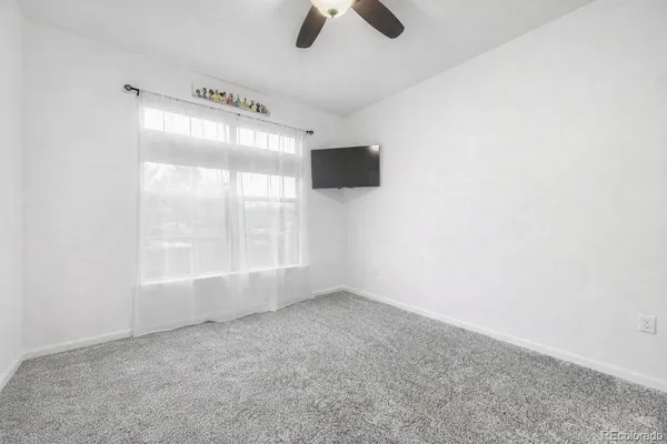 an empty room with windows and fan