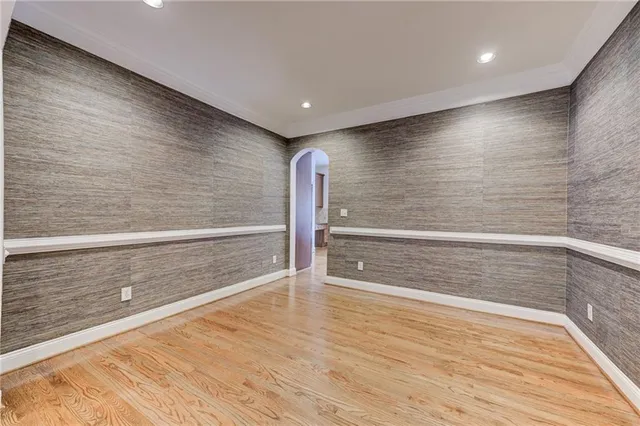 a view of an empty room with wooden floor and kitchen