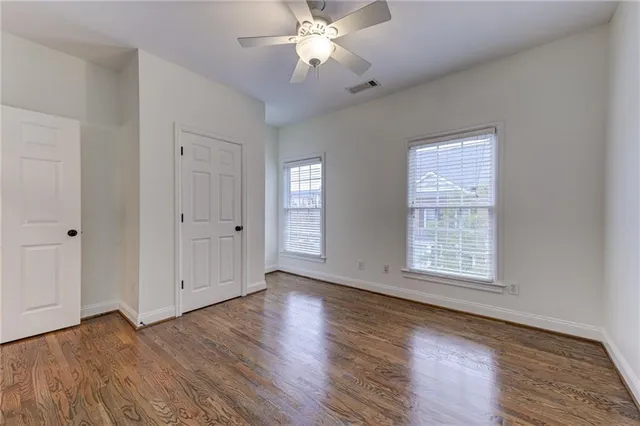 an empty room with wooden floor a ceiling fan and closet
