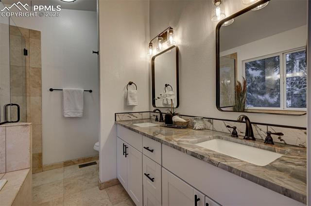 7790 Julynn Road Colorado Springs, CO 80919 - Photo 30 of 50 Luxurious remodeled Primary Bathroom with new toilet, dual sink vanity with quartz countertops, framed mirrors, tiled shower, and soaking tub.