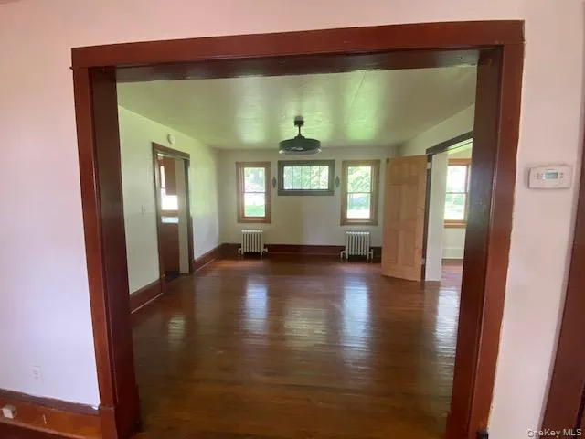 a view of empty room with wooden floor and fan