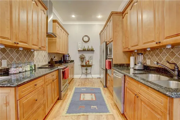 a kitchen with stainless steel appliances granite countertop a sink a stove and a wooden cabinets