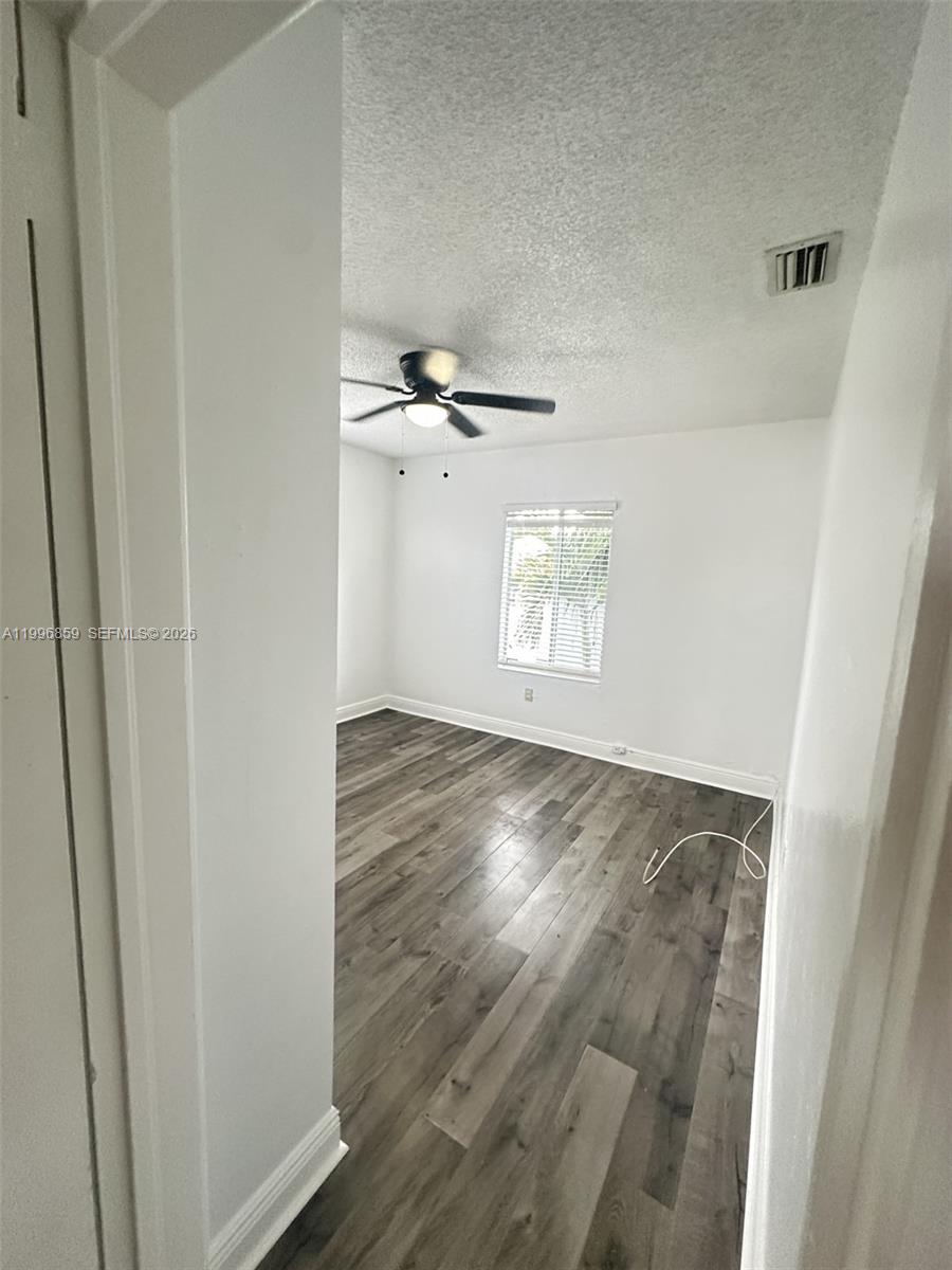 4232 Northwest 2nd Terrace, Unit A Miami, FL 33126 - Photo 9 of 11 an empty room with wooden floor cabinet and windows