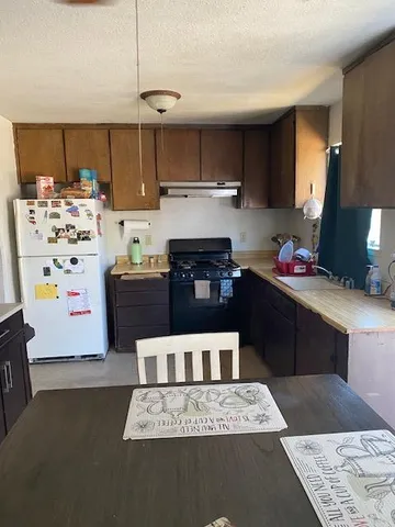 a kitchen with kitchen island granite countertop a sink stove and refrigerator