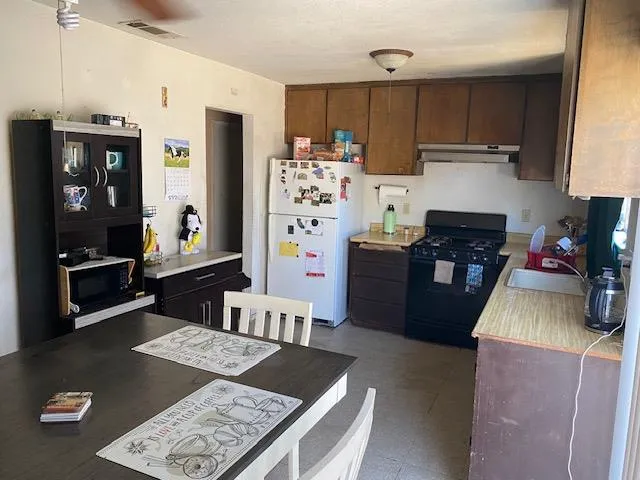 a kitchen with granite countertop a refrigerator stove and sink