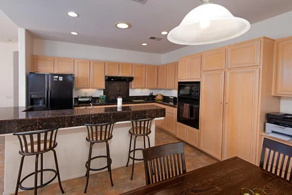 a kitchen with stainless steel appliances granite countertop a stove a refrigerator a sink a stove with white cabinets and wooden floor