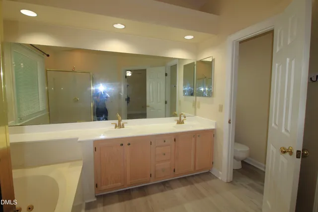 a spacious bathroom with a double vanity sink a toilet and a shower