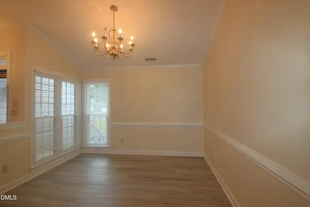 a view of a chandelier in big room with wooden floor