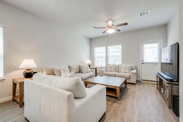 a living room with furniture a ceiling fan and a flat screen tv