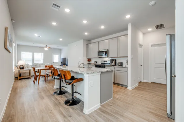 a living room with lots of furniture wooden floor and a view of kitchen