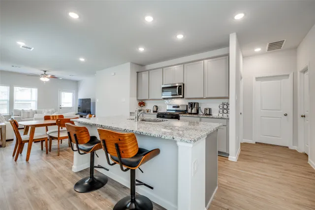 a kitchen with stainless steel appliances granite countertop a table chairs sink refrigerator and microwave