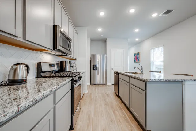 a kitchen with stainless steel appliances granite countertop a sink stove and refrigerator