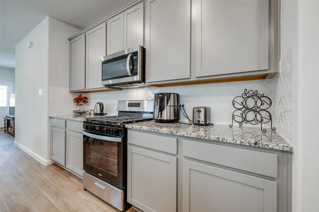 a kitchen with stainless steel appliances granite countertop white cabinets stove a sink and dishwasher