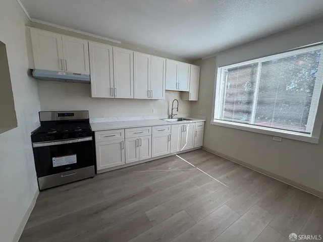 a kitchen with stainless steel appliances granite countertop a stove a sink and white cabinets