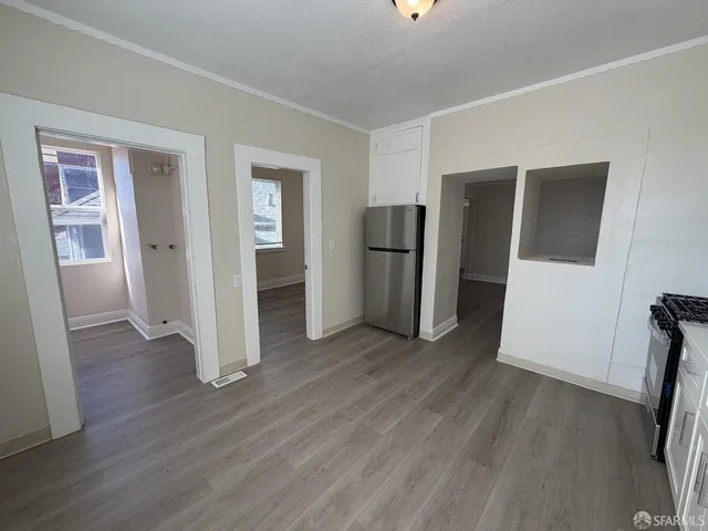 an empty room with wooden floor and a hallway