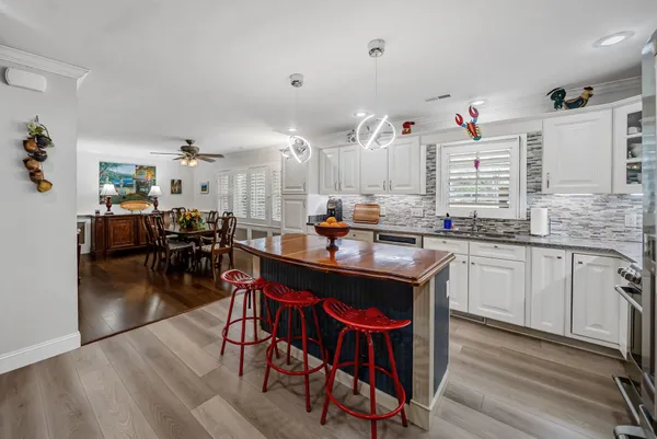 a kitchen with granite countertop lots of white furniture a dining table and chairs