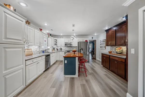 a kitchen with kitchen island granite countertop stainless steel appliances cabinets a sink and a stove