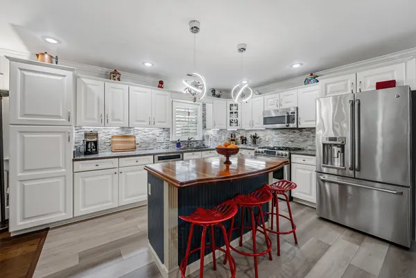 a kitchen with stainless steel appliances granite countertop a refrigerator a sink dishwasher a stove and white countertops with wooden floor