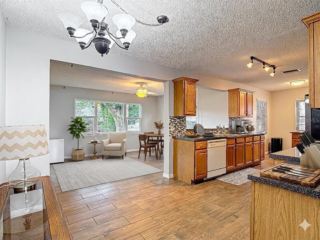 7318 Tranquil Drive Spring Hill, FL 34606 - Photo 11 of 38 a large kitchen with stainless steel appliances kitchen island granite countertop a sink dishwasher a stove a dining table and chairs with wooden floor