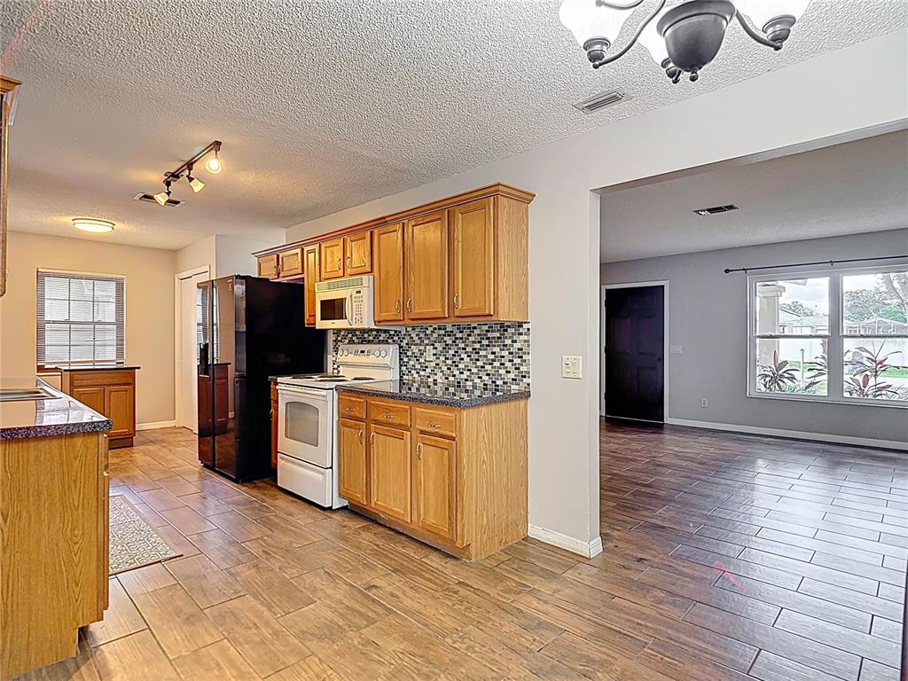7318 Tranquil Drive Spring Hill, FL 34606 - Photo 12 of 38 a kitchen with stainless steel appliances granite countertop a refrigerator and a stove top oven