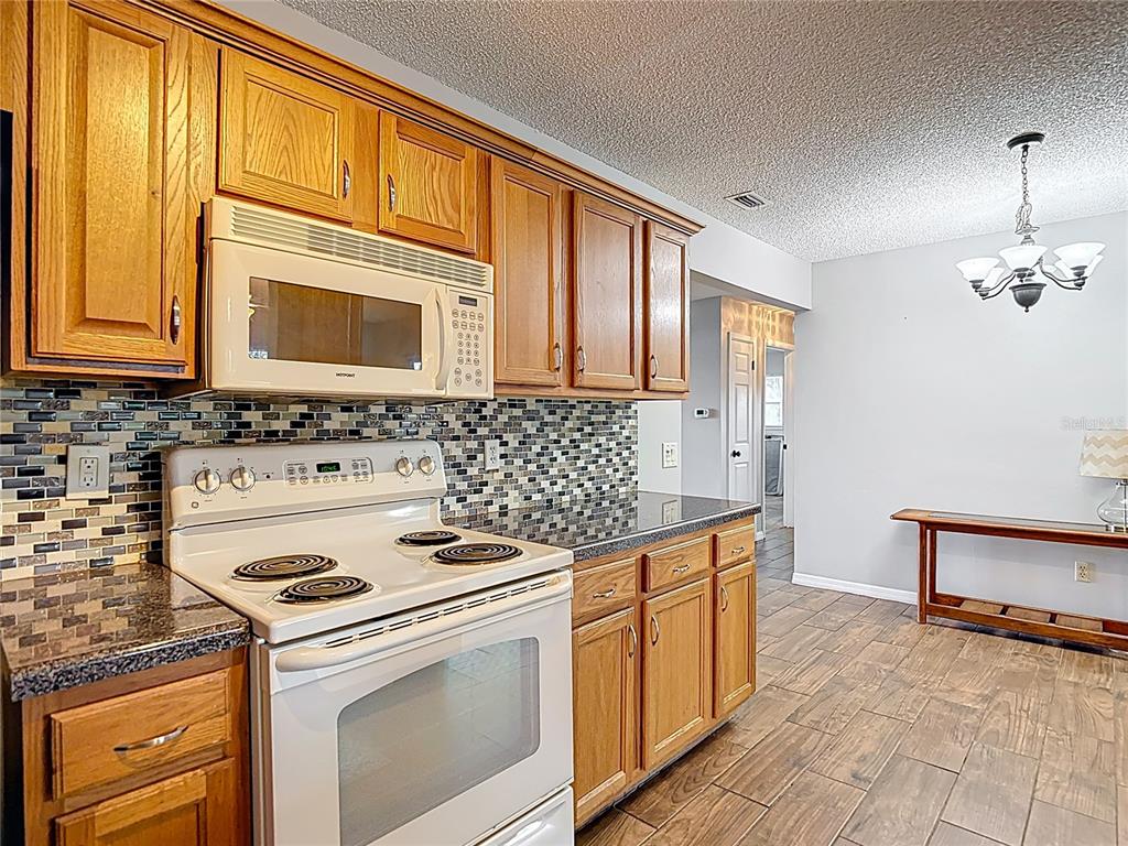 7318 Tranquil Drive Spring Hill, FL 34606 - Photo 17 of 38 a kitchen with stainless steel appliances granite countertop a stove and a microwave