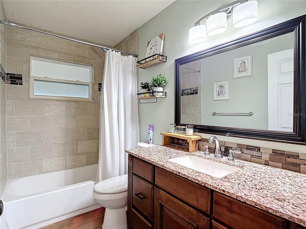 7318 Tranquil Drive Spring Hill, FL 34606 - Photo 19 of 31 a bathroom with a granite countertop sink toilet and shower