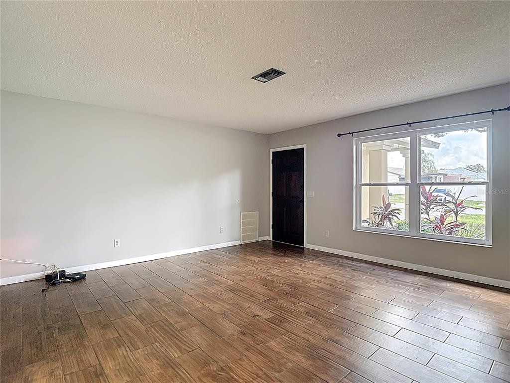 7318 Tranquil Drive Spring Hill, FL 34606 - Photo 6 of 38 an empty room with wooden floor and windows