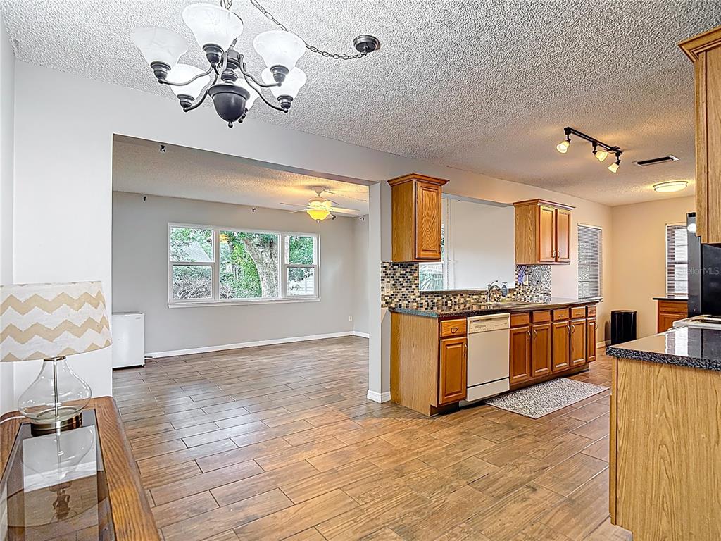 7318 Tranquil Drive Spring Hill, FL 34606 - Photo 7 of 31 a large kitchen with stainless steel appliances kitchen island granite countertop a sink dishwasher a stove a dining table and chairs with wooden floor