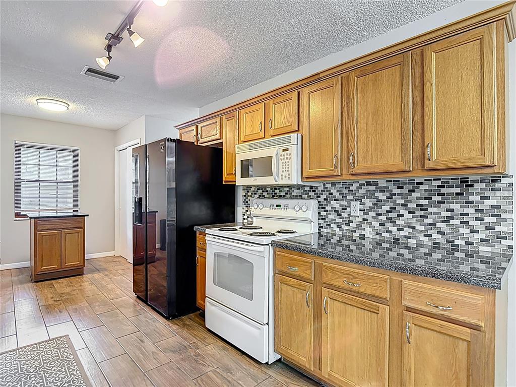 7318 Tranquil Drive Spring Hill, FL 34606 - Photo 10 of 38 a kitchen with stainless steel appliances granite countertop a refrigerator stove and sink