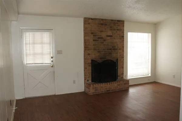 an empty room with wooden floor a fireplace and windows