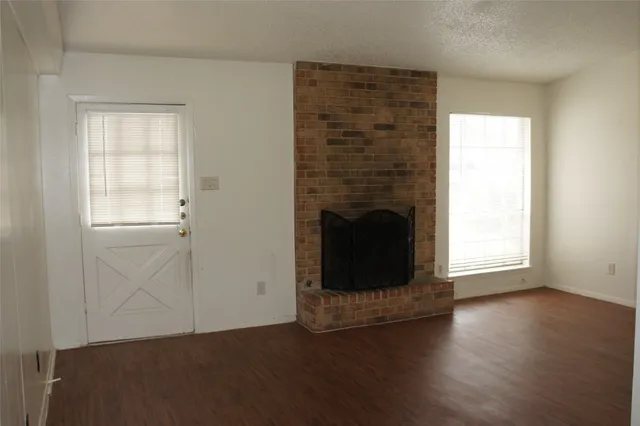 an empty room with wooden floor a fireplace and windows