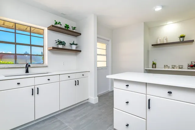a kitchen with white cabinets and window