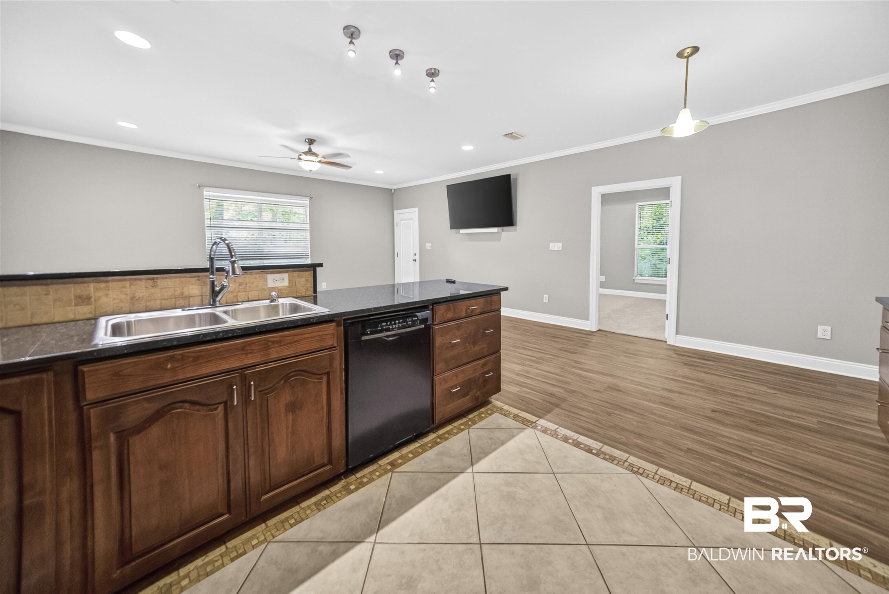 5913 Antoine Road Mobile, AL 36693 - Photo 9 of 33 Kitchen island featuring a double basin sink with a gooseneck faucet, black dishwasher, and dark wood cabinetry