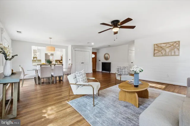 a living room with couches chairs and paintings on the wall with wooden floor