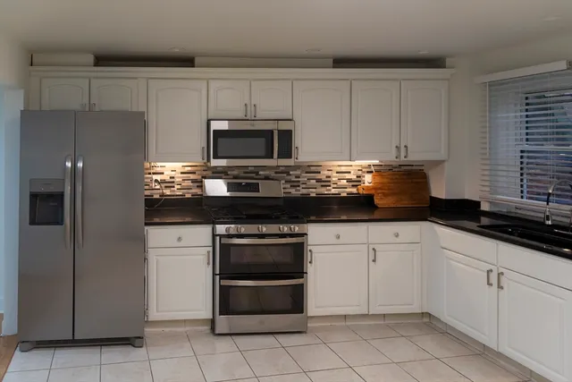 a kitchen with granite countertop white cabinets and stainless steel appliances