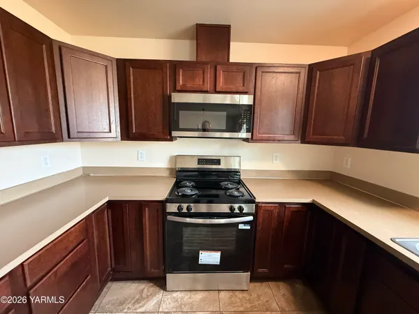 a large kitchen with stainless steel appliances granite countertop a stove top oven a sink and dishwasher