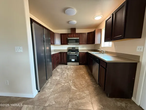 a kitchen with stainless steel appliances granite countertop wooden cabinets a stove top oven a sink and dishwasher